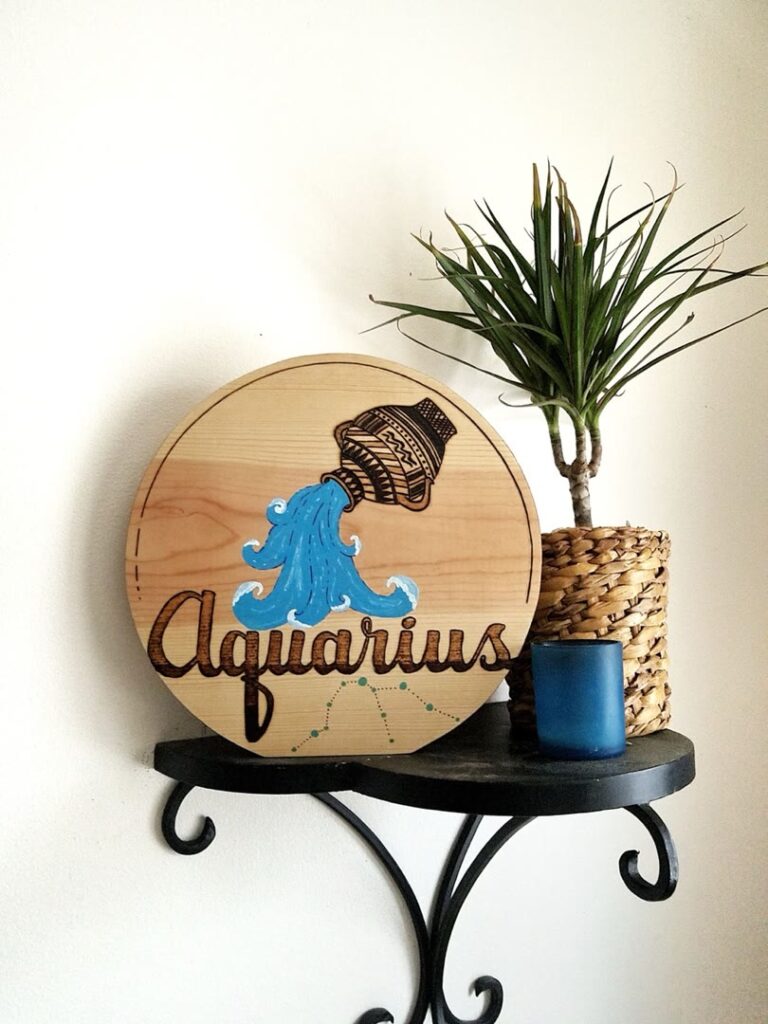 Hand-burned and painted Aquarius zodiac sign on round wood