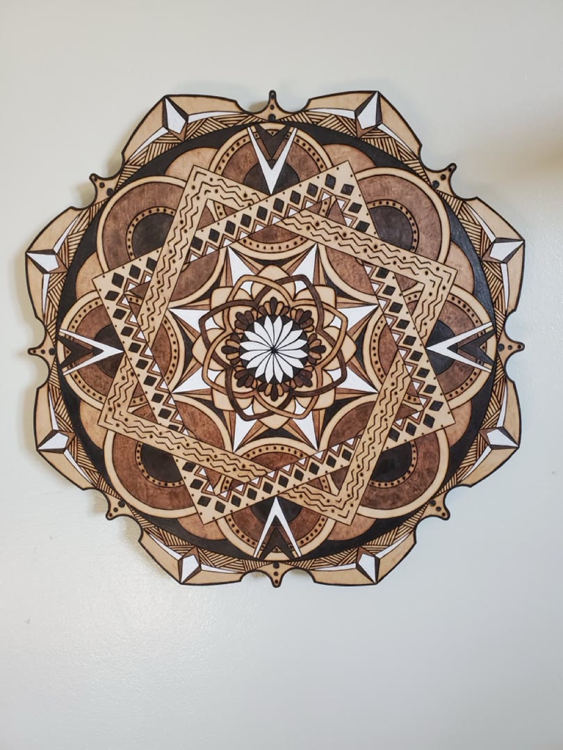 Front view of a detailed hand-burned geometric wood mandala