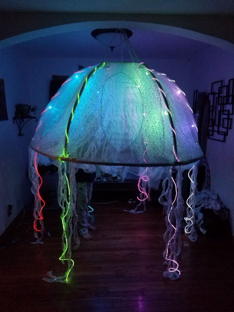 Suspended jellyfish-inspired light installation glowing in several colors