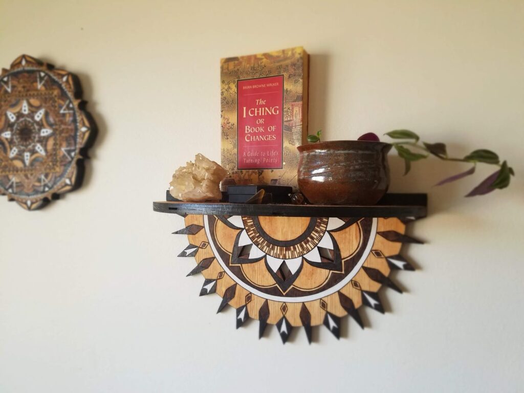 Decorative mandala shelf holding books crystals and a plant