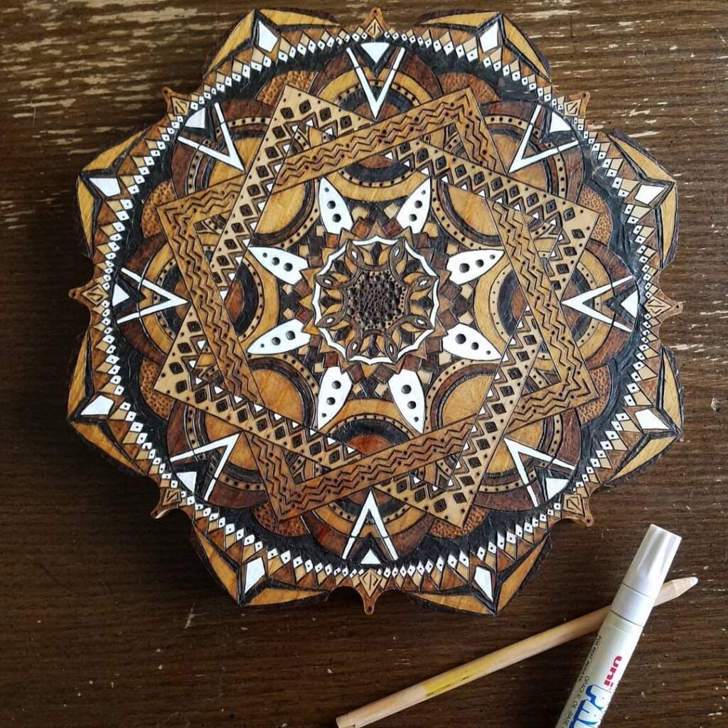 Intricate hand-drawn and burned geometric pattern on wood in progress